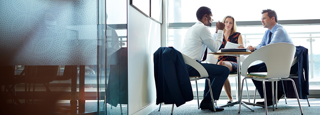hero-AboutUs business people at table with screens